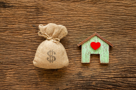 Home with red heart model and a big money bag put on the vintage wood background, Saving money for buy a new house or loan for plan business investment of real estate concept.