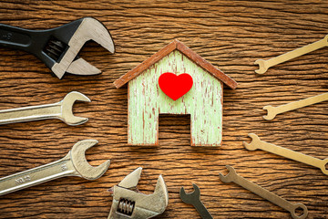 Wooden house with red heart and wrench put on the old wood, Loan for construction real estate and renovate the new home for family concept.