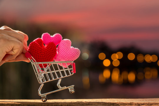 Man pushing a shopping cart and the heart put on inside put on the wood on beautiful bokeh background, Buy insurance or for give supporting when people get who lack of desire with love concept.