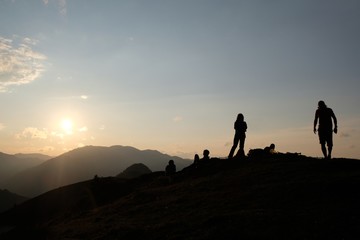 Black silhouette of tourists waiting for sunset on peak Lomis Mta in Borjomi-Kharagauli National Park, Georgia. 