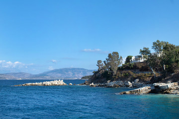 Naklejka premium Seascape - a cozy bay in the Ionian Sea, a white house on a rock, trees on the shore, Corfu, Greece
