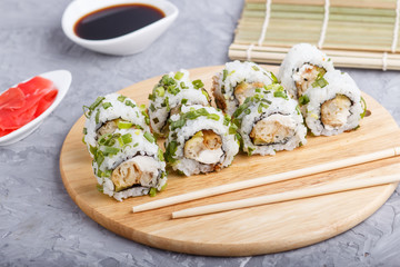 Japanese maki sushi rolls with green onion on wooden board on a gray concrete background. Side view