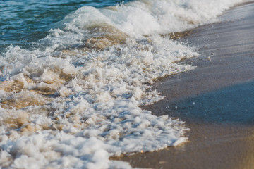 Close-up of a wave hitting a beach in warm sunset light