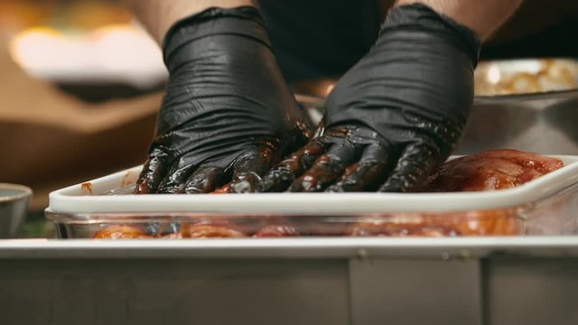 Professional chef marinating meat in a metal bowl in the kitchen of a fancy restaurant