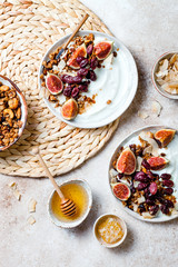 Breakfast bowls with granola, figs, roasted red grapes, yogurt, coconut chips and honey. Healthy vegan, vegetarian breakfast table