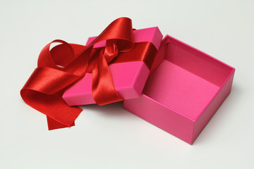Open pink carton gift box with red satin ribbon on white background. Unboxing. Christmas mood. Space for your goods. 