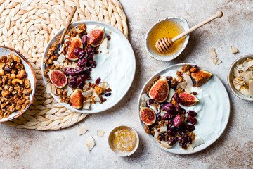 Breakfast bowls with granola, figs, roasted red grapes, yogurt, coconut chips and honey. Healthy...