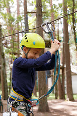 Young boy in helmet spend his leisure time in adventure playground.