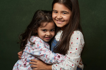 Two sisters portrait on green background with copy space