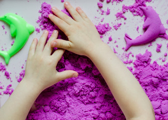 Obraz na płótnie Canvas Childs hands with sand. kid play kinetic sand. Violet sand. Magic sand. Close up