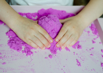 Obraz na płótnie Canvas Childs hands with sand. kid play kinetic sand. Violet sand. Magic sand. Close up