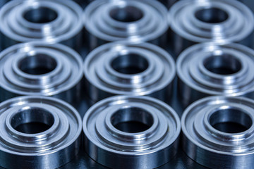 Abstract technical background for design and project. Metal parts machined on a lathe are laid out on a dark background. Machined industrial parts.