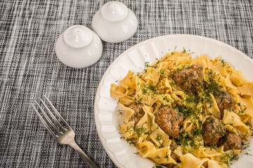 Tagliatelle pasta with pork meatballs and dill sauce. Selective focus.