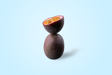 half sliced passion fruit balancing on one whole passion fruit on blue background