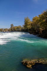 under a bright blue sky you can see the waterfall of Manavgat