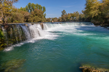 under a bright blue sky you can see the waterfall of Manavgat
