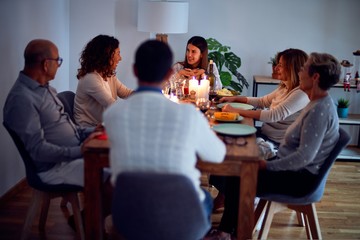 Family and friends dining at home celebrating christmas eve with traditional food and decoration, all sitting on the table together