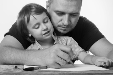 Parents should help the child succeed in elementary school. Father helping her daughter with her homework. Black and white image.