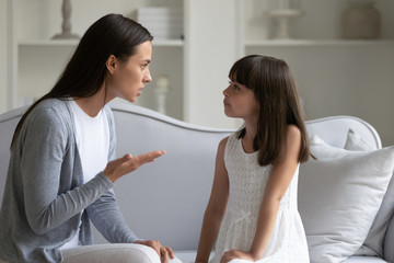 Irritated woman lecturing little stubborn daughter for bad behavior.
