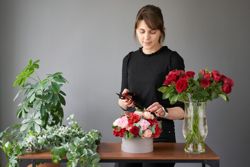 Woman creates flower arrangement in a round box. Beautiful bouquet of mixed flowers. Floral shop concept . Handsome fresh bunch. Flowers delivery