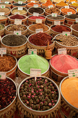 many vessels filled with spices in various colors are offered from an oriental bazaar