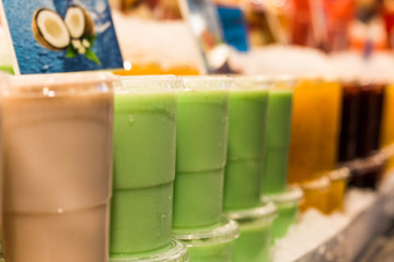 A variety of different colorful fruit smoothies at the farmers market stall