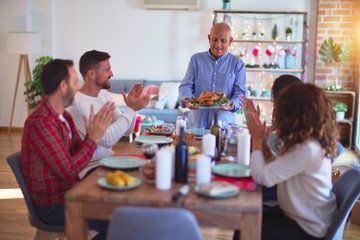 Beautiful family smiling happy and confident. Showing roasted turkey and applauding celebrating Christmas at home