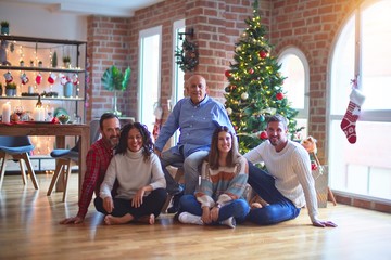 Beautiful family smiling happy and confident. Sitting on the floor and posing with tree celebrating Christmas at home