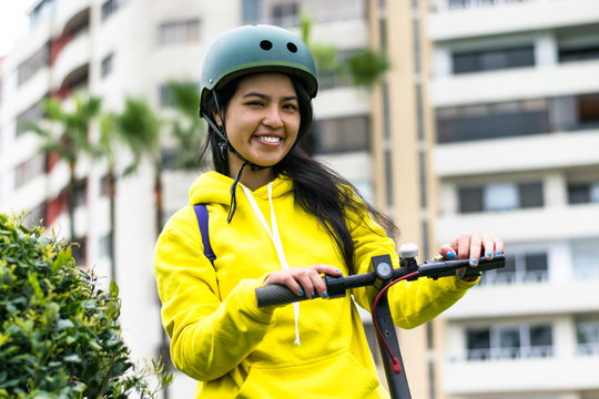 Laughing young woman with helmet on an electric scooter