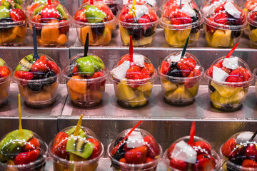 A variety of different colorful fruit salad cocktails at the farmers market stall