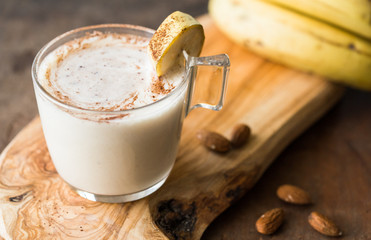 Fresh Made Chocolate Banana Smoothie on a wooden table. Selective focus. Milkshake with nuts. Protein diet. Healthy food and drink concep