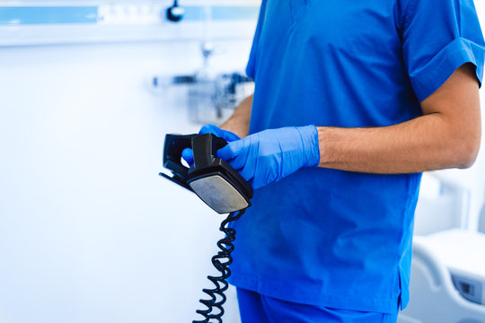 Defibrolator in hands. Blue medical clothes. First aid. External Pacer Analyzer,Using a defibrillator to save lives.