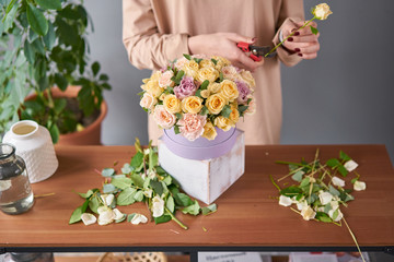 Florist woman creates flower arrangement in a round box. Beautiful bouquet of mixed flowers. Floral shop concept . Handsome fresh bunch. Flowers delivery