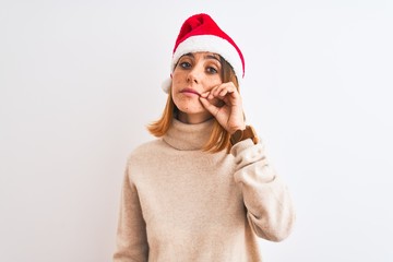Beautiful redhead woman wearing christmas hat over isolated background mouth and lips shut as zip...