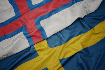 waving colorful flag of sweden and national flag of faroe islands.