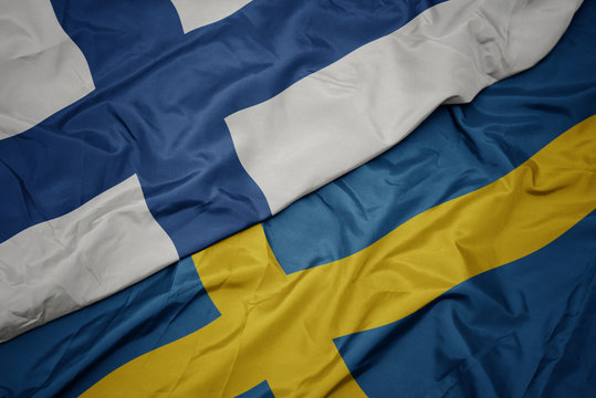 waving colorful flag of sweden and national flag of finland.