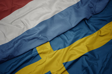 waving colorful flag of sweden and national flag of luxembourg.