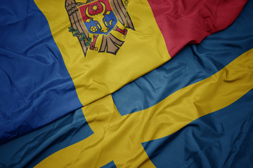 waving colorful flag of sweden and national flag of moldova.