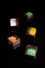 Art colorful chocolate candies on black background, selected focus