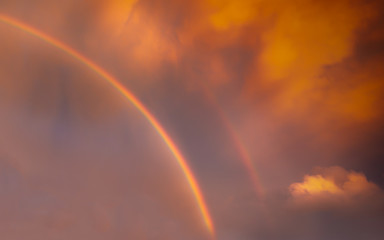 A rainbow and a hint of its double on a stormy evening at sunset.