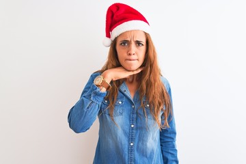 Young beautiful redhead woman wearing christmas hat over isolated background cutting throat with hand as knife, threaten aggression with furious violence
