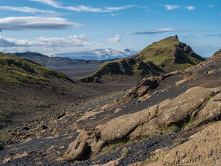 Icelandic lava desert landscape with view on Tindfjallajokull glacier mountains and green hills. Fjallabak Nature Reserve, Iceland. Summer blue sky
