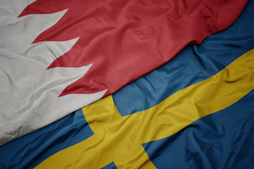waving colorful flag of sweden and national flag of bahrain.