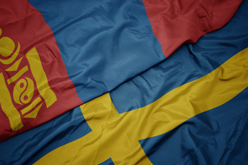 waving colorful flag of sweden and national flag of mongolia.