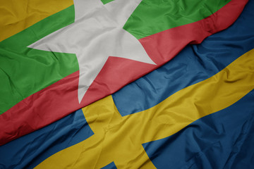waving colorful flag of sweden and national flag of myanmar.