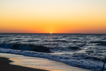 Sunrise over the Black sea, waves on the sandy beach.