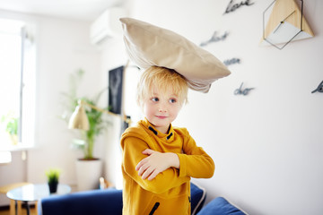 Pillow fight. Mischievous preschooler child jumping on a sofa and hitting with pillows.Active games for child at home.