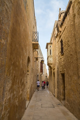 Tourists Exploring a Narrow Quiet Street of the Medieval City of Mdina (Malta)
