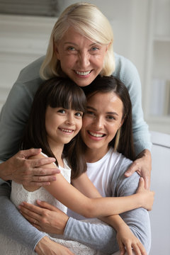 Vertical image happy middle aged woman cuddling daughter and grandchild.
