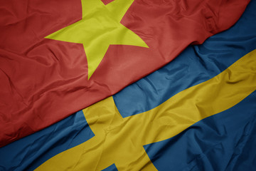 waving colorful flag of sweden and national flag of vietnam.